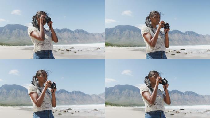 一位非洲裔美国妇女在海滩上用数码相机拍照