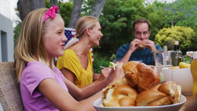 微笑的白人女孩在花园里吃家庭庆祝餐