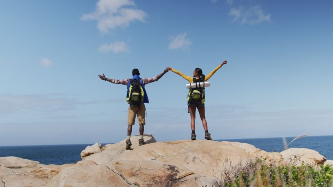 非洲裔美国夫妇站在岩石上，双臂张开，徒步旅行