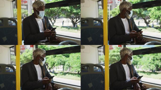非裔美国老人戴着口罩坐在公交车上使用智能手机