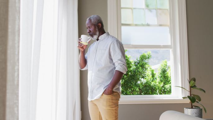 非裔美国老人喝着咖啡，看着窗外