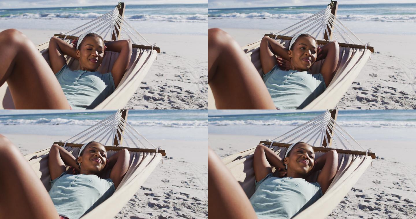 一位非洲裔美国妇女微笑着躺在沙滩上的吊床上