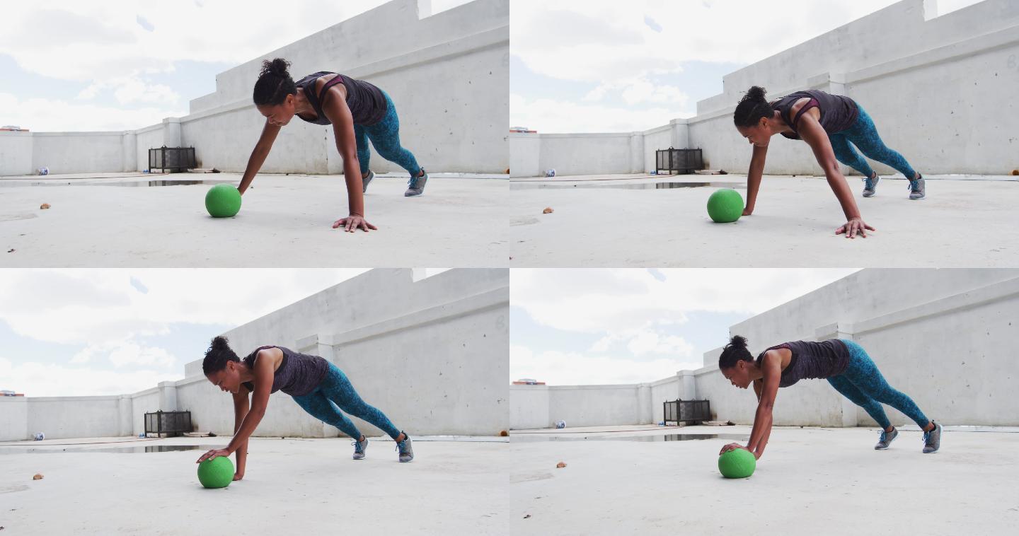 一个非裔美国妇女在一个空的城市建筑里用实心球做俯卧撑