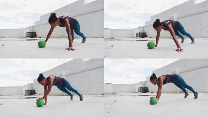 一个非裔美国妇女在一个空的城市建筑里用实心球做俯卧撑
