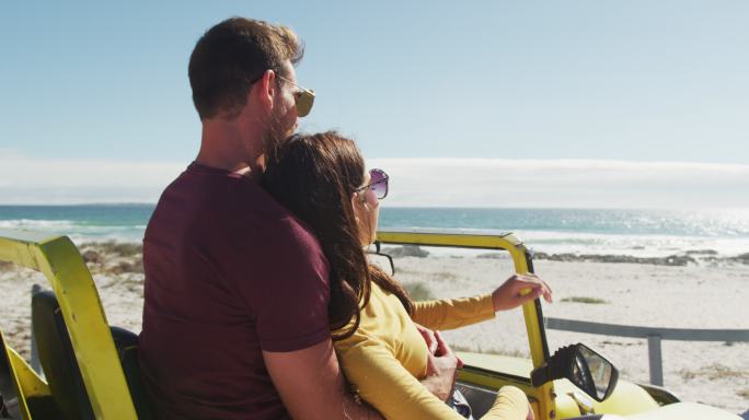 幸福的白人夫妇坐在沙滩车在海边聊天