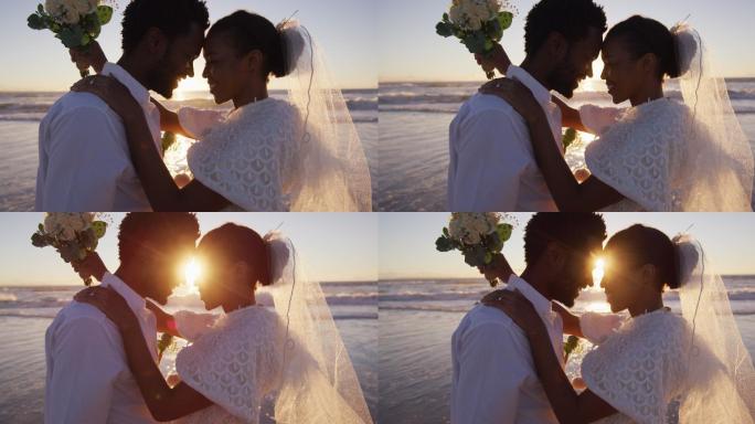 相爱的非裔美国人结婚了，在日落时分的海滩上看着对方