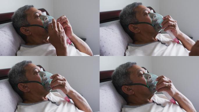 高级混血男子躺在家里的床上使用口罩呼吸机