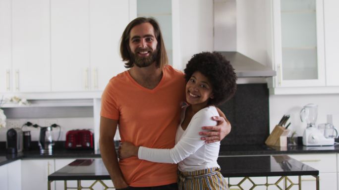 混血夫妇在厨房里微笑拥抱的肖像