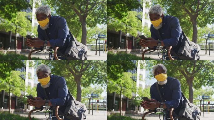 非裔美国老人戴着口罩，倚靠在自行车上使用智能手机