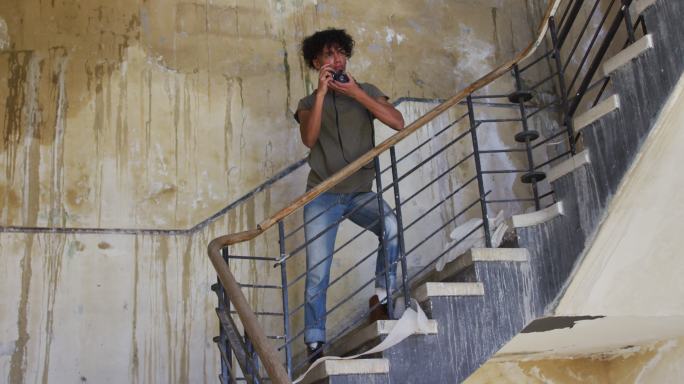 一名非裔美国男子站在楼梯上用数码相机拍照