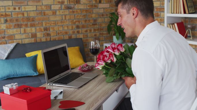 白人男子用笔记本电脑打视频电话手捧鲜花，飞吻