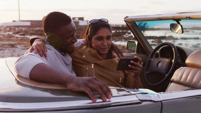 一对非洲裔美国夫妇坐在路上的敞篷车里自拍