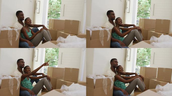 快乐的非裔美国人夫妇拥抱交谈坐在地板上与包装盒