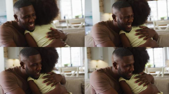 非洲裔美国人的女儿和她的父亲微笑着拥抱在沙发上