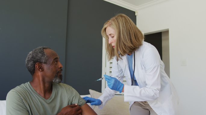 白种高级女医生给非裔美国高级男病人接种疫苗