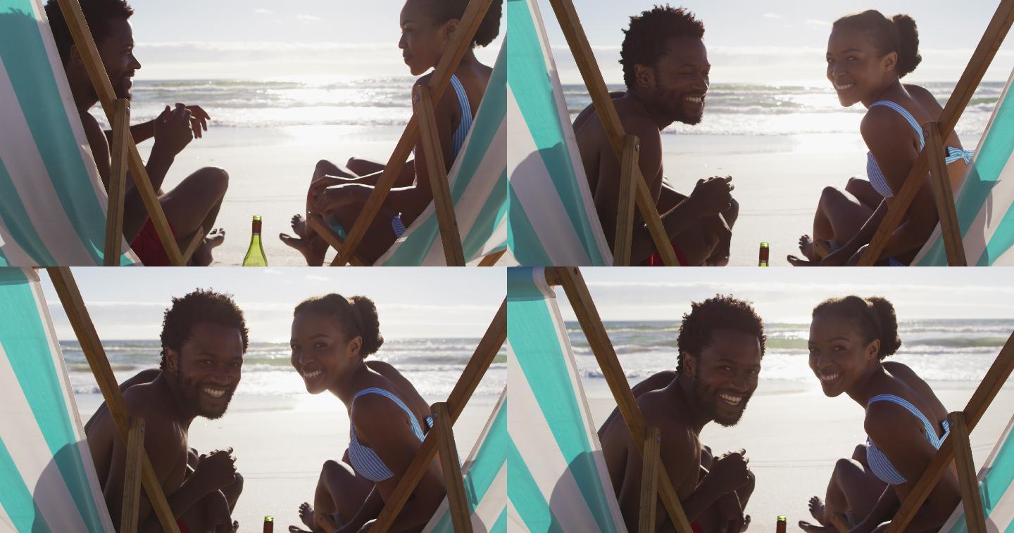 非裔美国夫妇微笑着坐在沙滩上的躺椅上的肖像