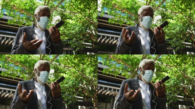非裔美国高级男子戴着口罩在公司园区用智能手机聊天