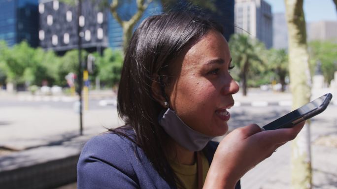 非裔美国妇女戴着面具在街上用智能手机聊天