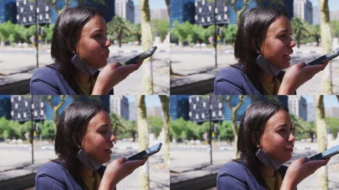 非裔美国妇女戴着面具在街上用智能手机聊天
