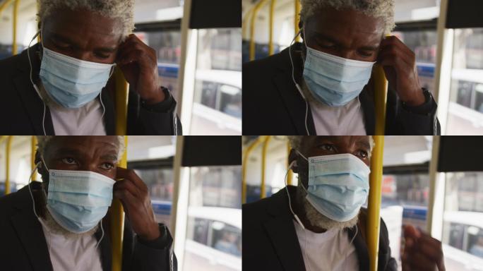 非裔美国老人戴着口罩，戴着耳机站在公共汽车上