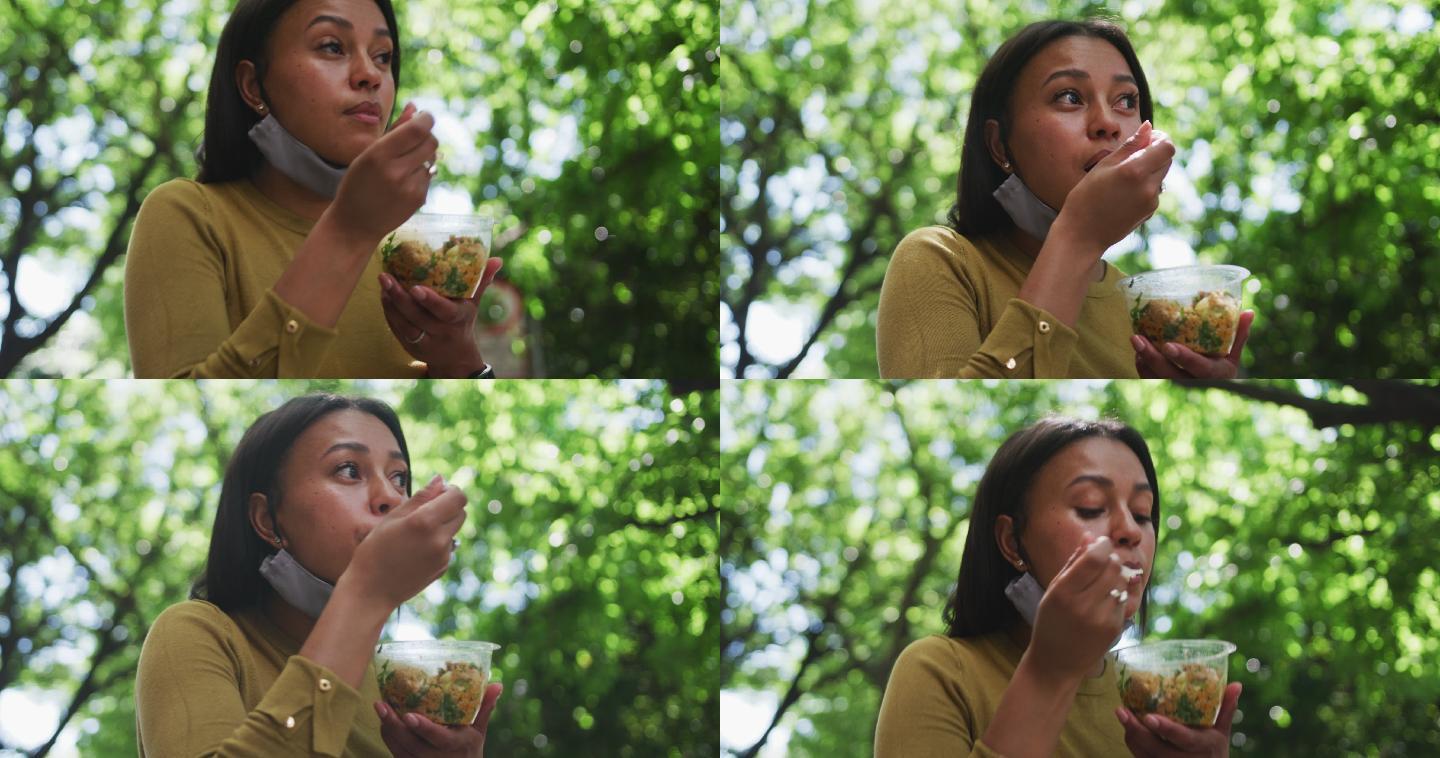 非洲裔美国妇女戴着口罩在大学公园吃沙拉