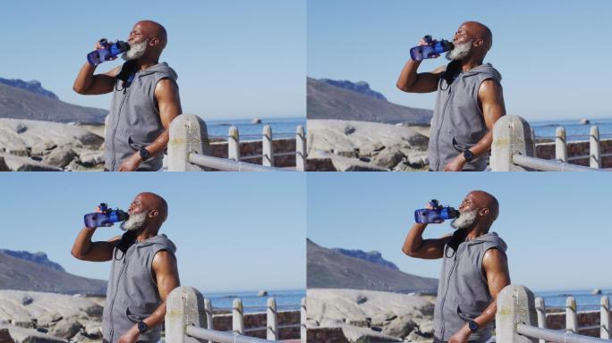 资深非洲裔美国人在海边的岩石上锻炼喝水