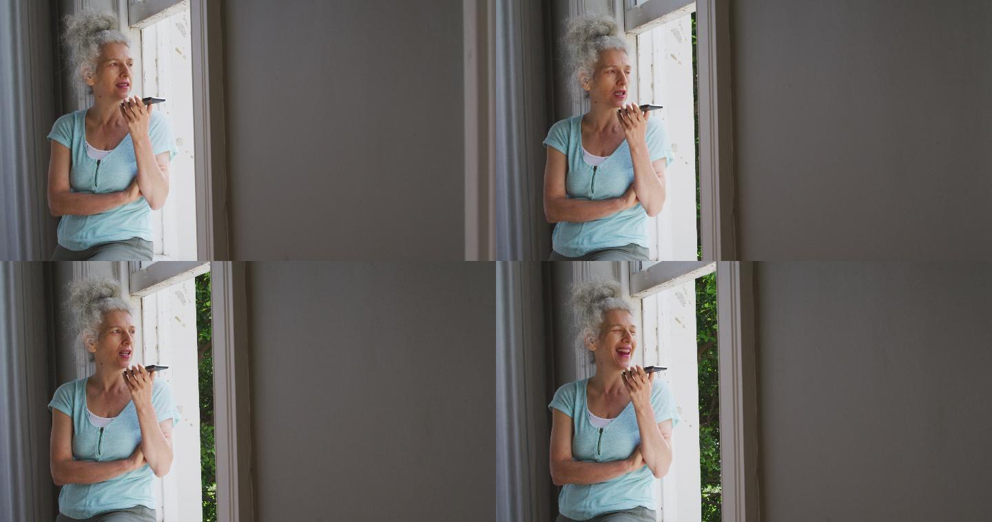 一个白人老太太在家靠窗边用智能手机聊天