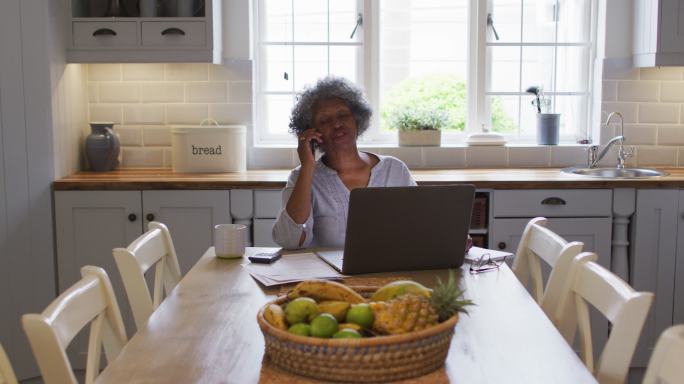 高级非洲裔美国女性在家里用笔记本电脑和智能手机聊天