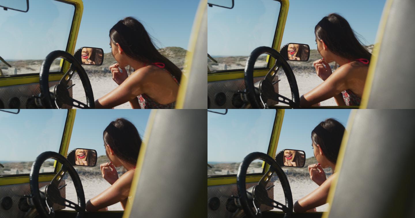 快乐的白人女人坐在沙滩车在海边做化妆