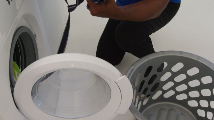 非裔美国老人从家里的洗衣机里拿出干净的衣服