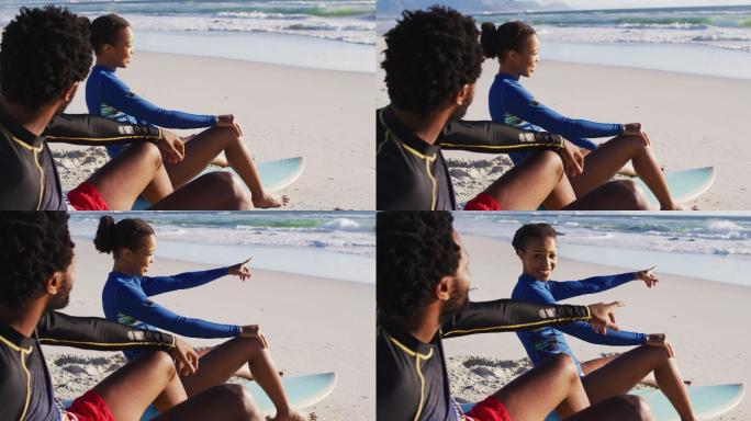 一对非洲裔美国夫妇在海滩上聊天，坐在冲浪板上