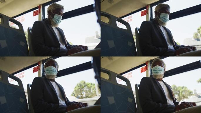 非裔美国老人戴着口罩坐在公交车上用笔记本电脑