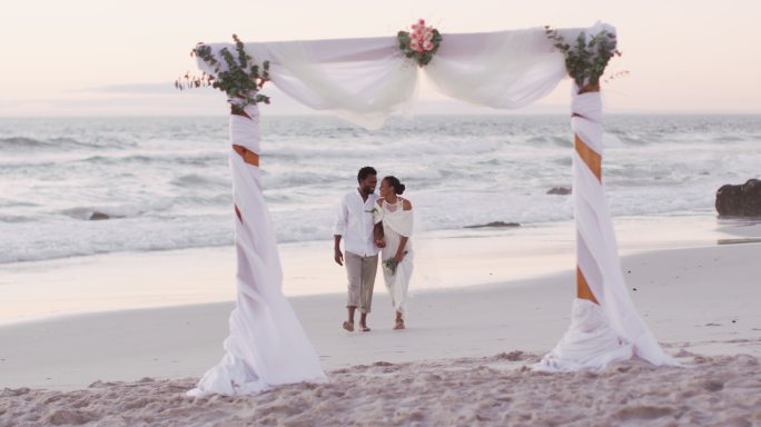 非裔美国情侣结婚，手牵着手在海滩上散步