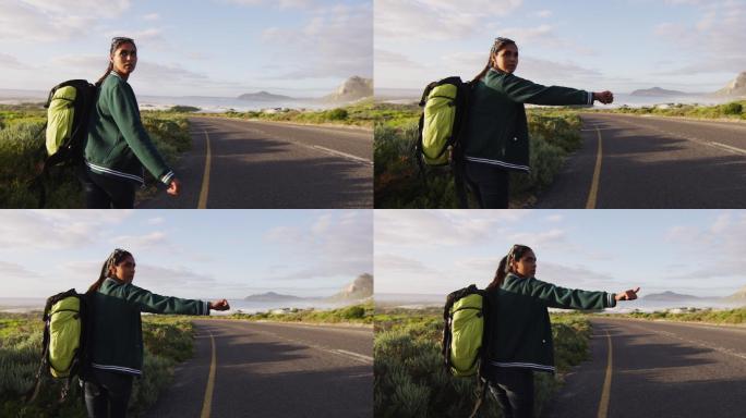 非裔美国妇女背着背包，站在路上想搭车
