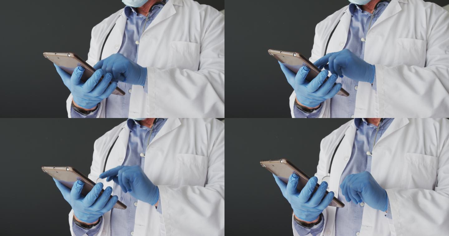 中段白种人男性医生戴着手术手套使用数码平板电脑