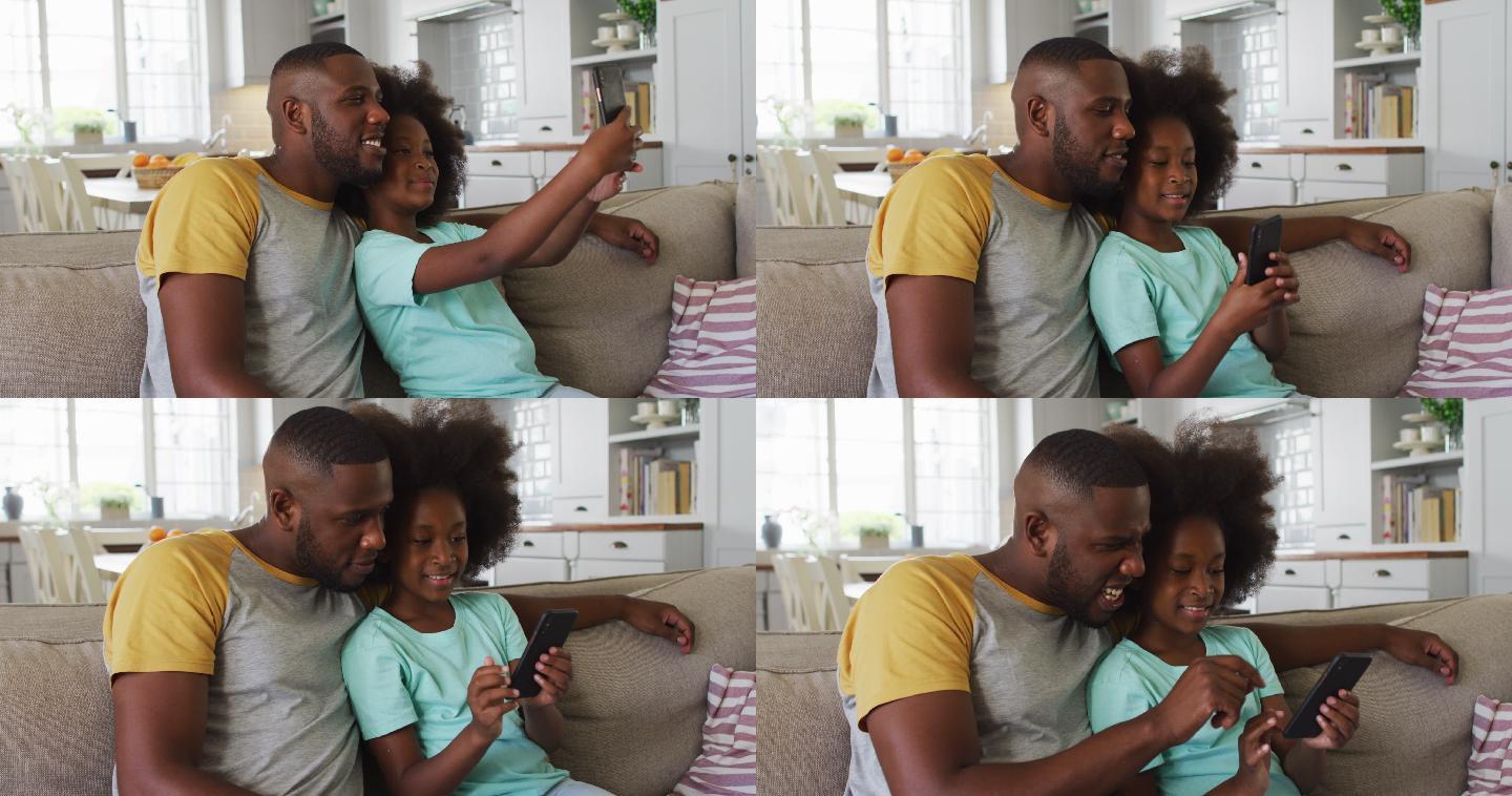 非裔美国人的女儿和她的父亲一起坐在沙发上使用智能手机