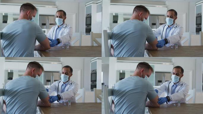 混血男医生戴着口罩在家给男性病人接种疫苗
