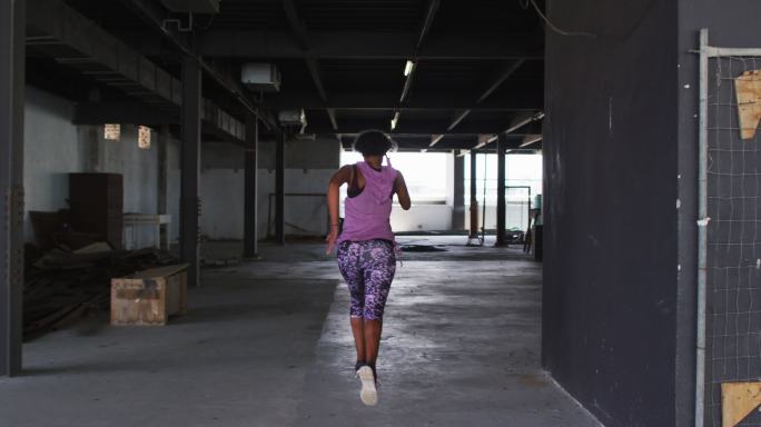一位身穿运动服的非裔美国妇女在空旷的城市建筑中慢跑