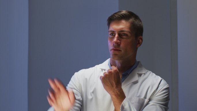 英俊的白种男医生穿着实验服正在使用虚拟数字接口查看信息