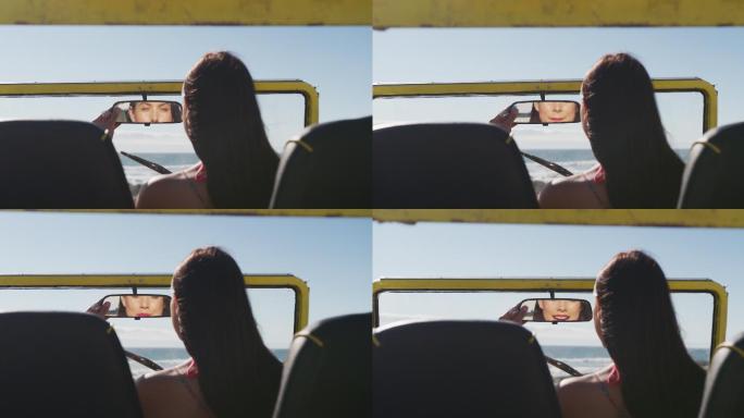 快乐的白人女人坐在沙滩车在海边做化妆
