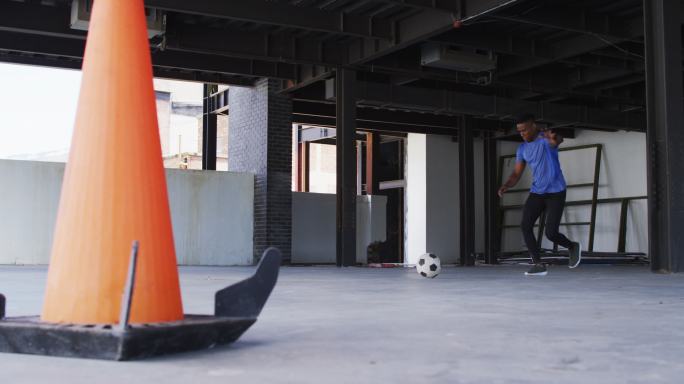 一个非裔美国人在一座空的城市建筑里踢足球