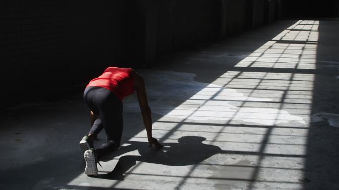 一个非裔美国人跪在一幢空房子里开始跑步