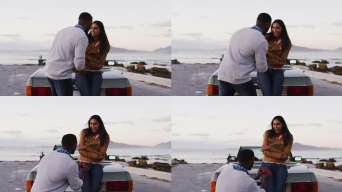 一名非洲裔美国男子在公路上敞篷车旁用戒指向女友求婚