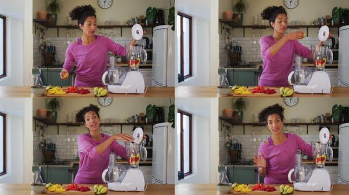 一名混血儿妇女把切好的水果放进家里厨房的果汁机里