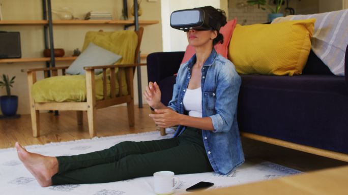 一个带着虚拟现实头盔的白人女人，坐在家里的地板上