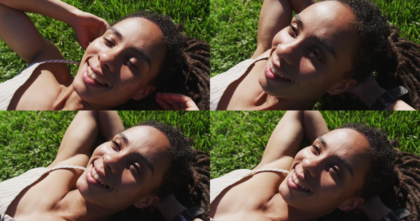 近距离的非洲裔美国妇女躺在草地上，在公园微笑
