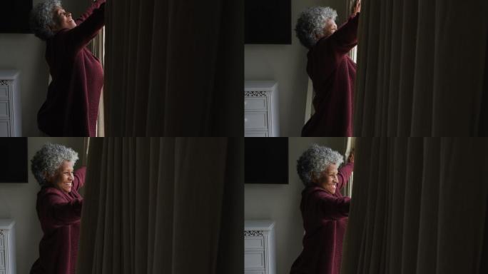 一位年长的非洲裔美国妇女正在拉开家里的窗帘