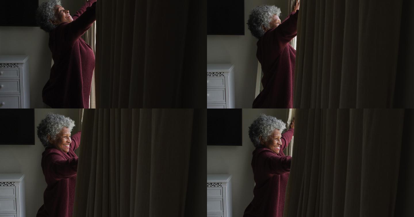 一位年长的非洲裔美国妇女正在拉开家里的窗帘