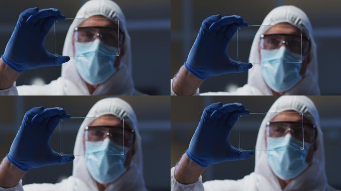 白种男性医务工作者，穿着防护服，戴着手套，在实验室使用手持接口