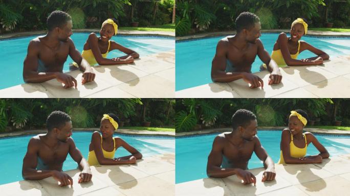 快乐的非裔美国夫妇站在游泳池交谈和微笑在阳光灿烂的花园